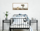 Minimalist bedroom with black metal bed frame, white and blue bedding, nightstands, and framed Joshua tree landscape above bed on white wall.