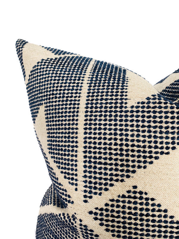 Close-up of a beige pillow cover featuring an indigo blue geometric pattern of small dots forming diagonal stripes and triangles.