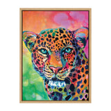 Vibrant close-up portrait of a leopard with blue eyes and a multicolored spotted fur against a bright pink and green background, framed in light wood.