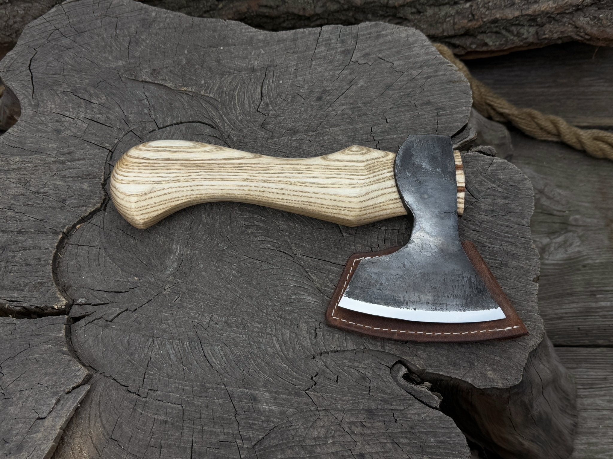 Small carving axe with carbon steel blade and ash wood handle, featuring leather sheath with belt loop