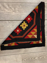 Small square Mexican hand woven kilim rug in red, yellow, black, and tan geometric floral patterns, folded to show both front and back sides on wood floor.
