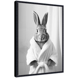 Black and white portrait of a rabbit wearing a tied white bathrobe, facing forward with upright ears and detailed fur texture.