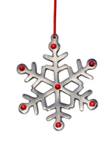 Silver metal snowflake Christmas ornament with six points, decorated with six small red gems and hanging from a thin red string against a white background.