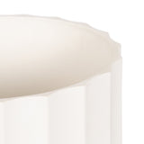 Close-up of the top edge of a white cylindrical vase with vertical ridged texture and an irregular, wavy rim