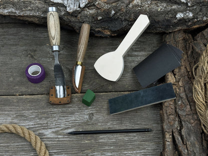 Spoon Carving Kit with bent gouge, whittling knife, wooden blank, sandpaper, sharpening board, pencil, and finger wrap