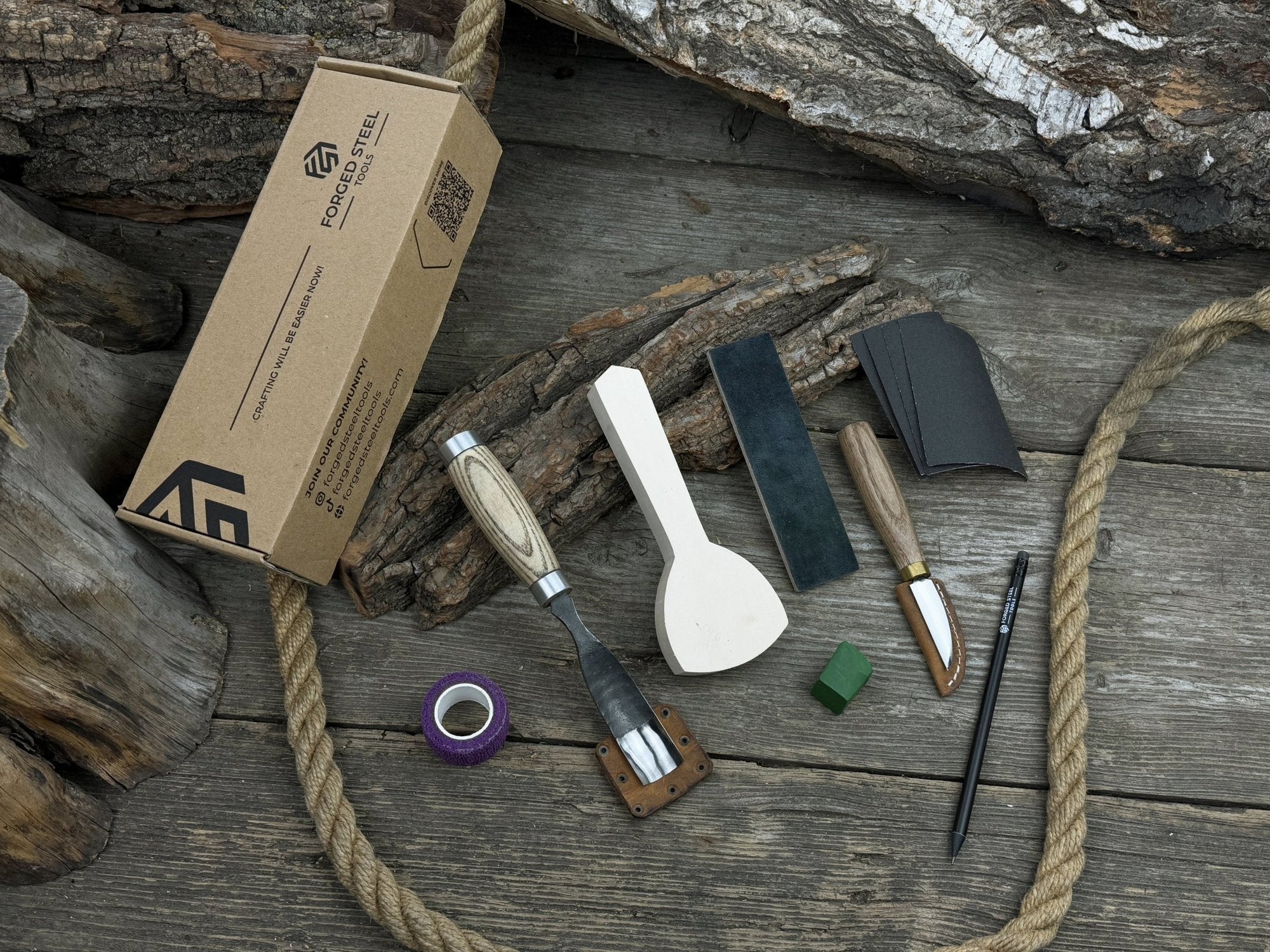 Spoon Carving Kit with bent gouge, whittling knife, wooden blank, sandpaper, sharpening board, pencil, and finger wrap