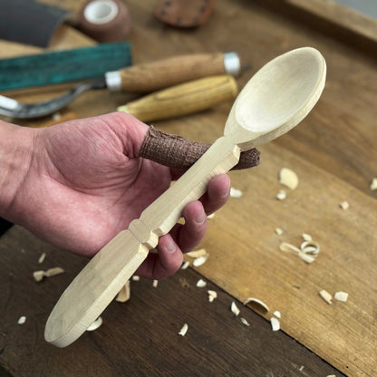 Complete Spoon Carving Kit with bent gouge, whittling knife, wooden blank, sandpaper, sharpening board, pencil, and finger wrap