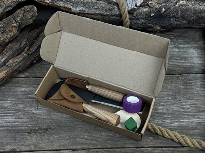 Spoon Carving Kit with knives, wooden blank, sandpaper, sharpening board, pencil, and finger wrap