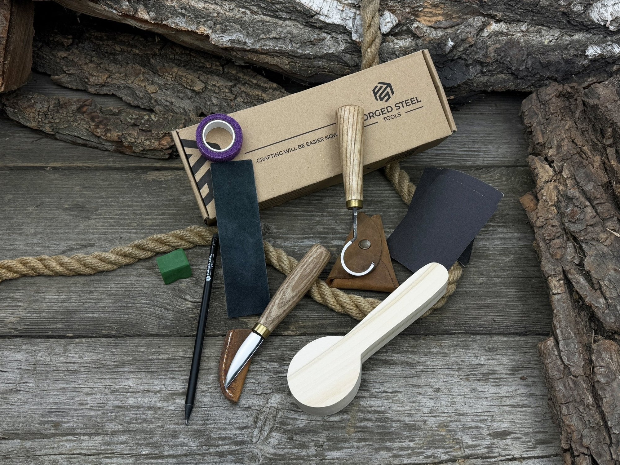 Spoon Carving Kit with knives, wooden blank, sandpaper, sharpening board, pencil, and finger wrap