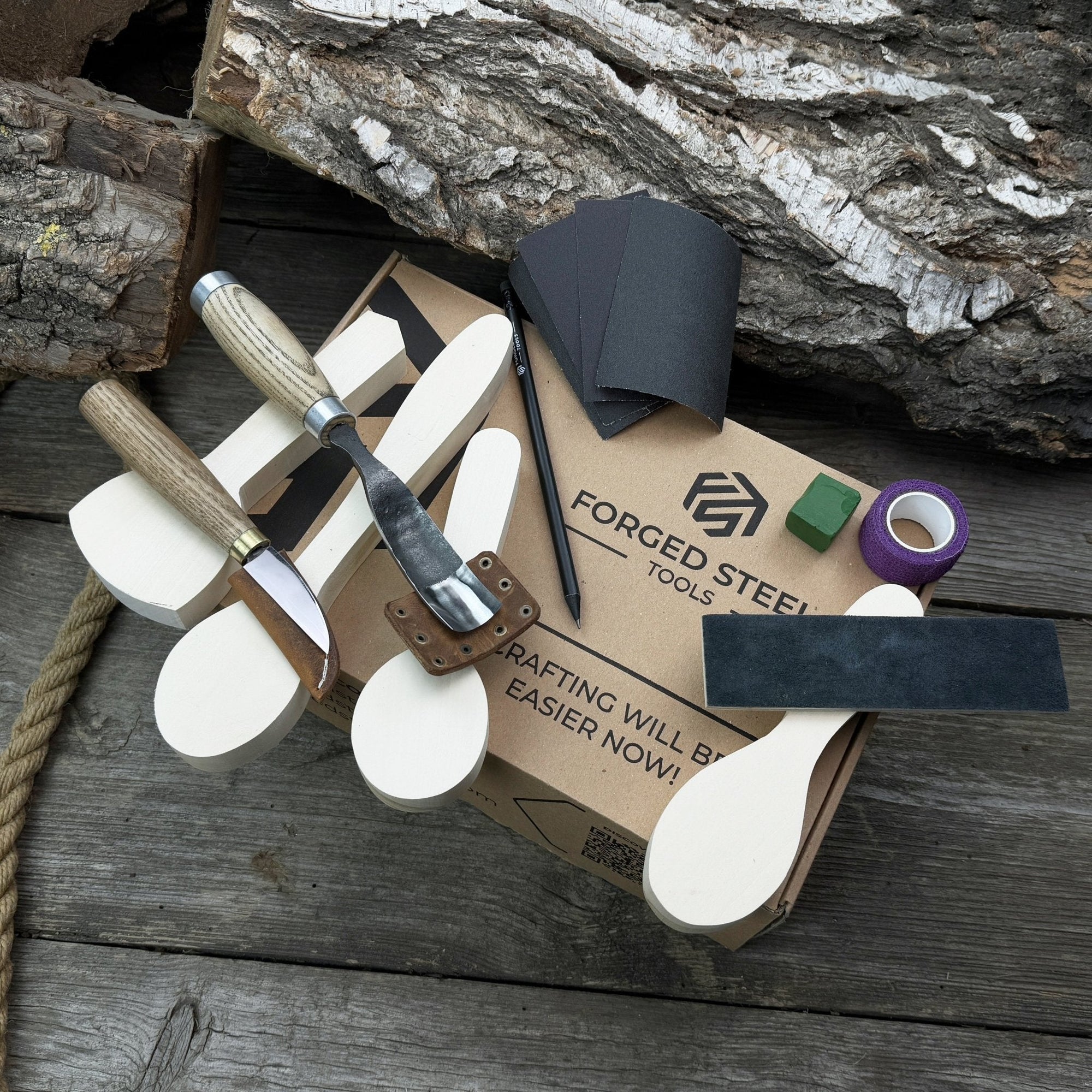 Spoon Carving Kit with hand-forged tools, wooden blanks, sandpaper, and sharpening board