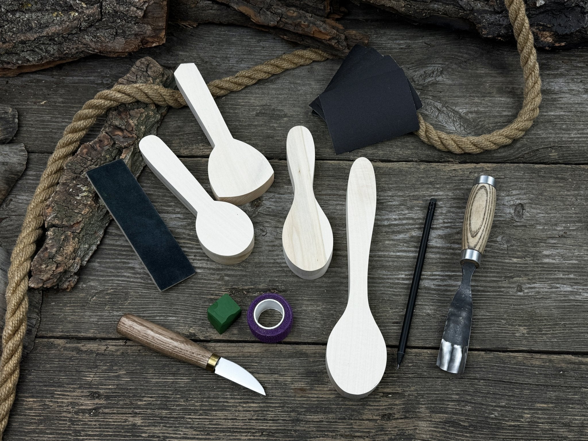 Spoon Carving Kit with hand-forged tools, wooden blanks, sandpaper, and sharpening board