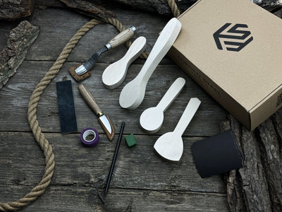 Spoon Carving Kit with hand-forged tools, wooden blanks, sandpaper, and sharpening board