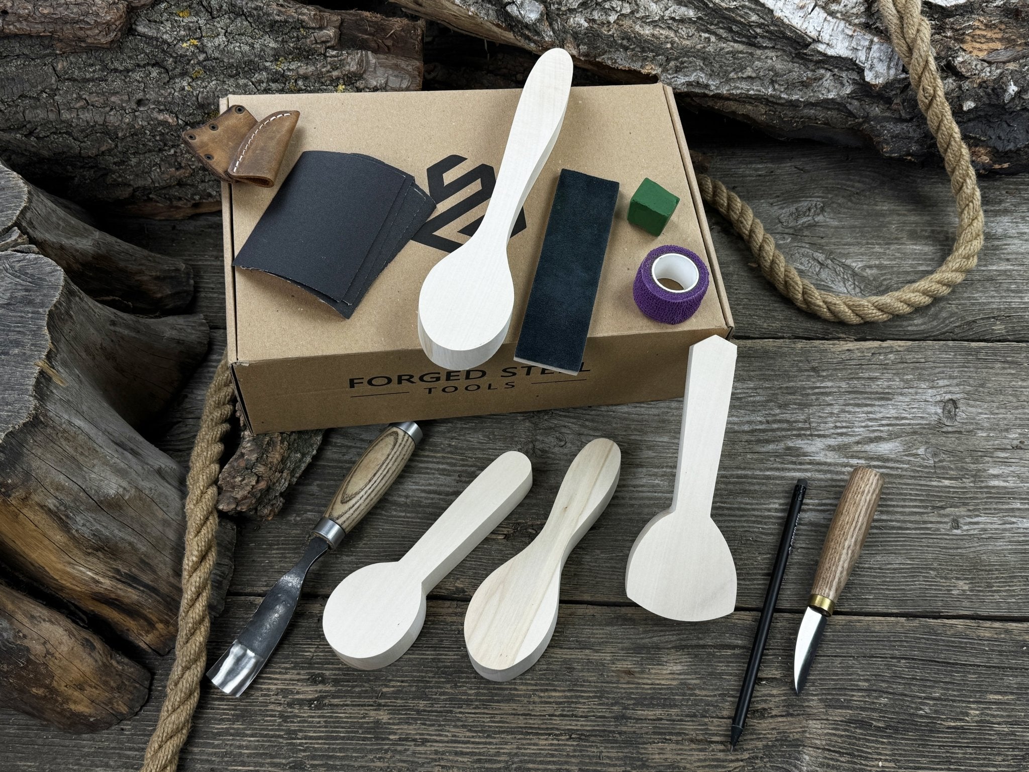 Spoon Carving Kit with hand-forged tools, wooden blanks, sandpaper, and sharpening board