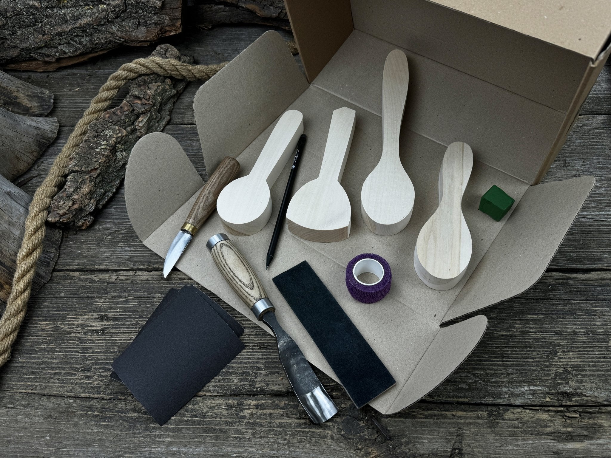 Spoon Carving Kit with hand-forged tools, wooden blanks, sandpaper, and sharpening board