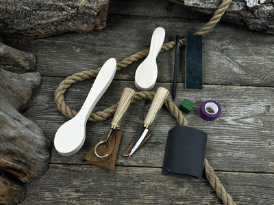 Complete spoon carving kit with knives, wooden blanks, sandpaper, sharpening board, pencil, and finger wrap
