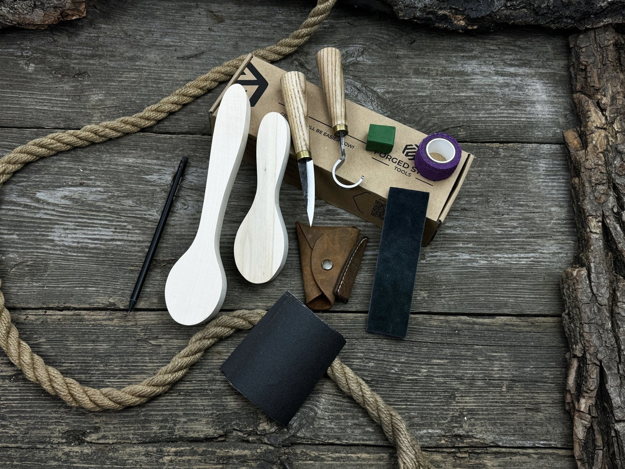 Complete spoon carving kit with knives, wooden blanks, sandpaper, sharpening board, pencil, and finger wrap