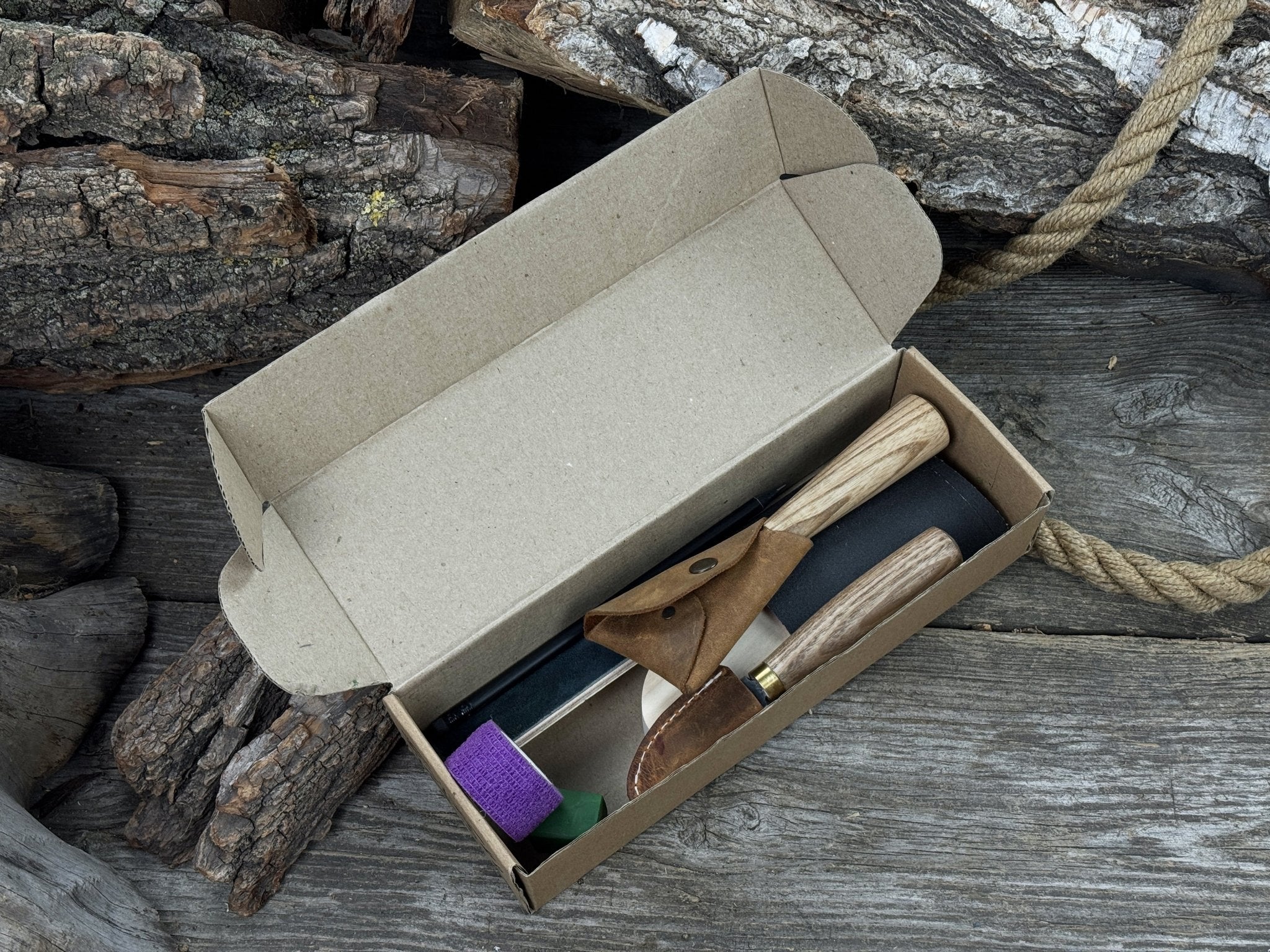 Spoon Carving Kit with knives, wooden blank, sandpaper, sharpening board, pencil, and finger wrap