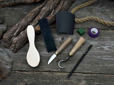Spoon Carving Kit with knives, wooden blank, sandpaper, sharpening board, pencil, and finger wrap