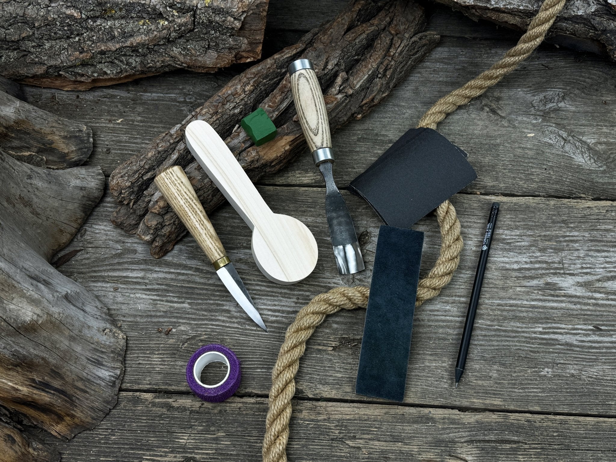 Spoon Carving Kit with knives, wooden blank, sandpaper, sharpening board, pencil, and finger wrap