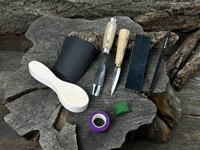 Spoon carving kit with sharpened tools, wooden blank, sandpaper, sharpening board, pencil, and finger wrap