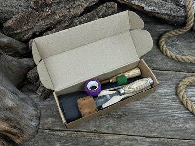Spoon carving kit with sharpened tools, wooden blank, sandpaper, sharpening board, pencil, and finger wrap