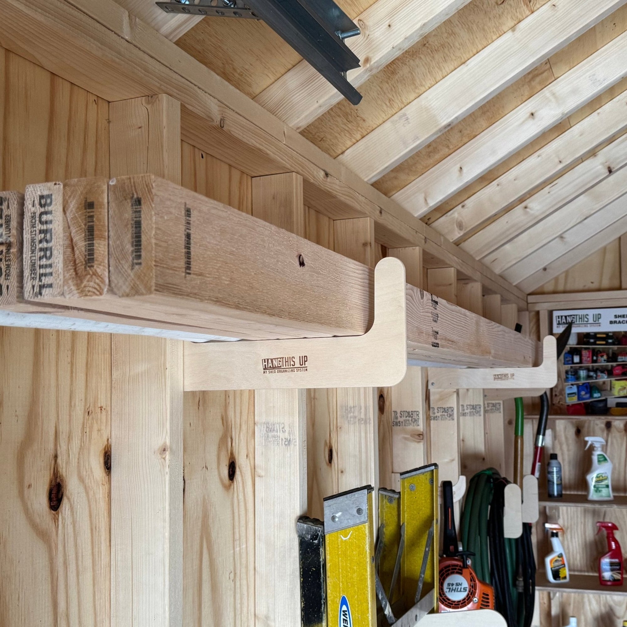 Stud Mounted Shed Storage Organizer brackets holding pipes and lumber inside a shed