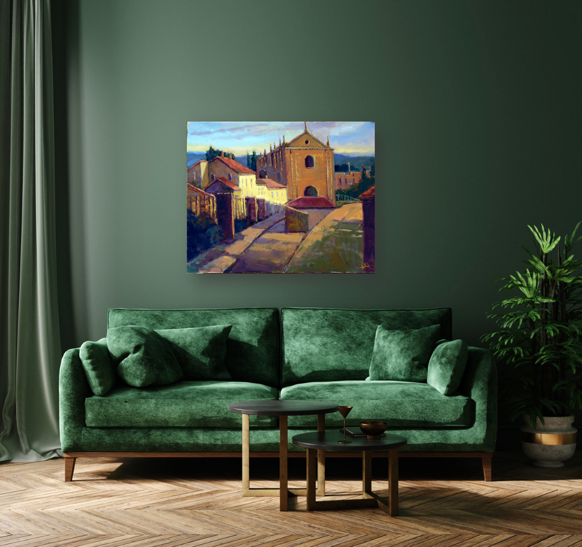Canvas print of a sunlit Portuguese street with an ochre church, white houses, and blue sky, hanging on a muted green wall above a dark green velvet sofa.