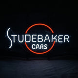 Neon sign glowing with white text 'STUDEBAKER CARS' and an incomplete red circle behind the word 'BAKER' on a black background.