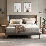 Contemporary bedroom with a gray upholstered bed, beige and cream bedding, two framed deer head prints above the headboard, and warm wood and neutral decor accents.