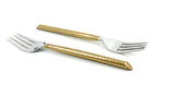 Two dinner forks with shiny silver heads and long hammered golden handles, shown on a white background at opposing angles.