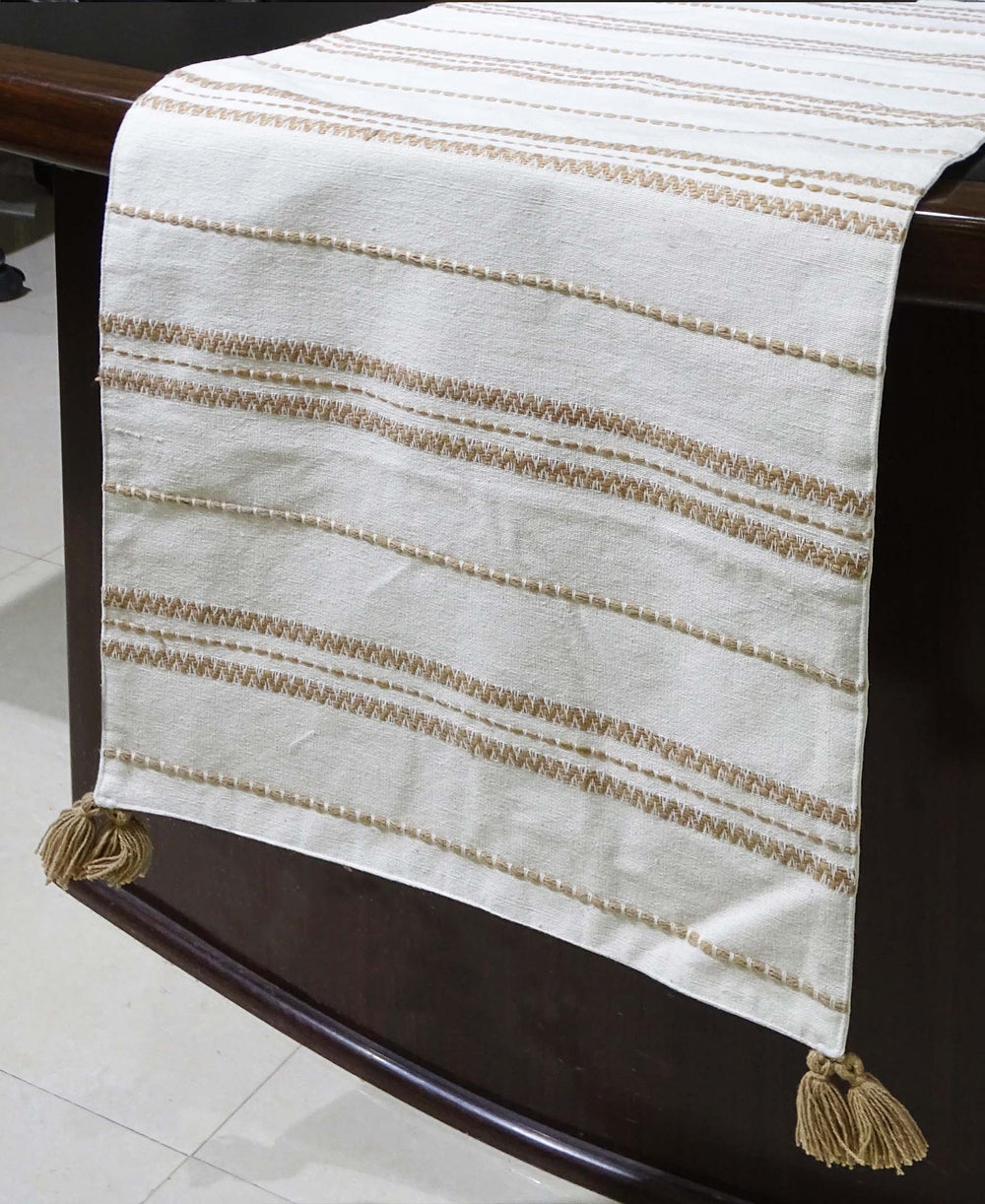 Beige off-white embroidered cotton table runner laid on a dining table with place settings