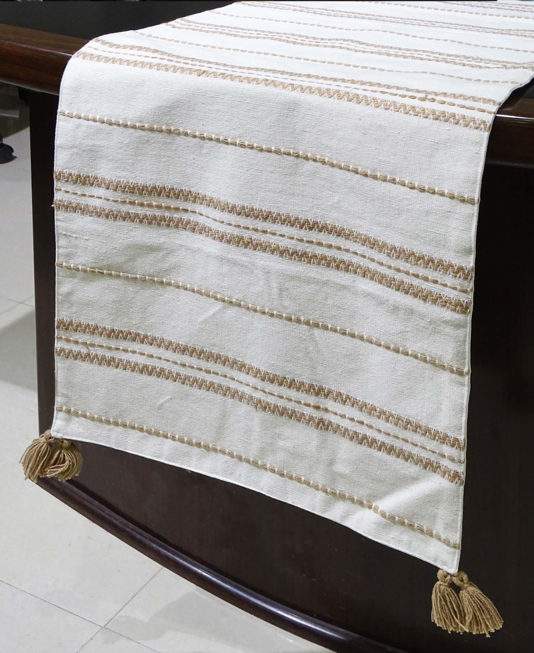 Beige off-white embroidered cotton table runner laid on a dining table with place settings