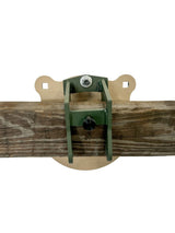 Metal target mount holding a weathered wooden beam horizontally against a beige background, secured with bolts and a central tightening knob.