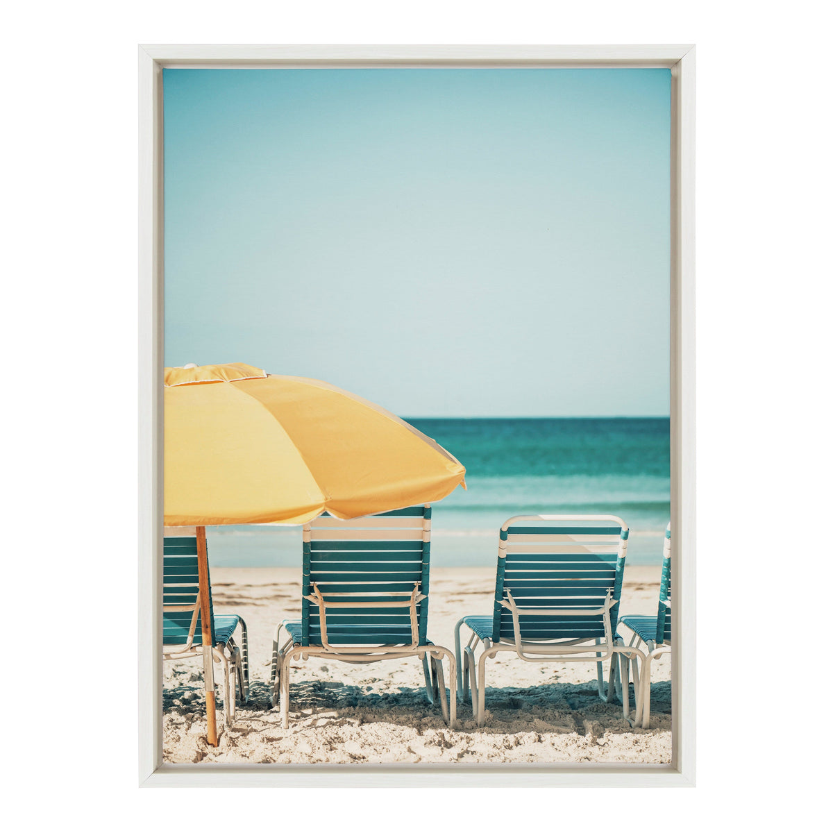 View of striped blue and white beach chairs and a large yellow umbrella on sandy shore facing calm turquoise ocean under clear blue sky.
