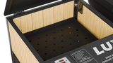 Interior view of a black-framed cold plunge tub with light wood paneling and perforated black bottom surface, featuring a digital control panel on the edge.