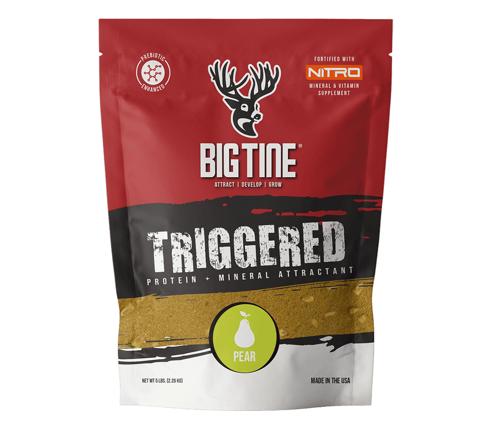 Red, black, and white bag of BIG TINE TRIGGERED protein and mineral attractant with pear flavor, featuring a deer head logo and green pear icon on front