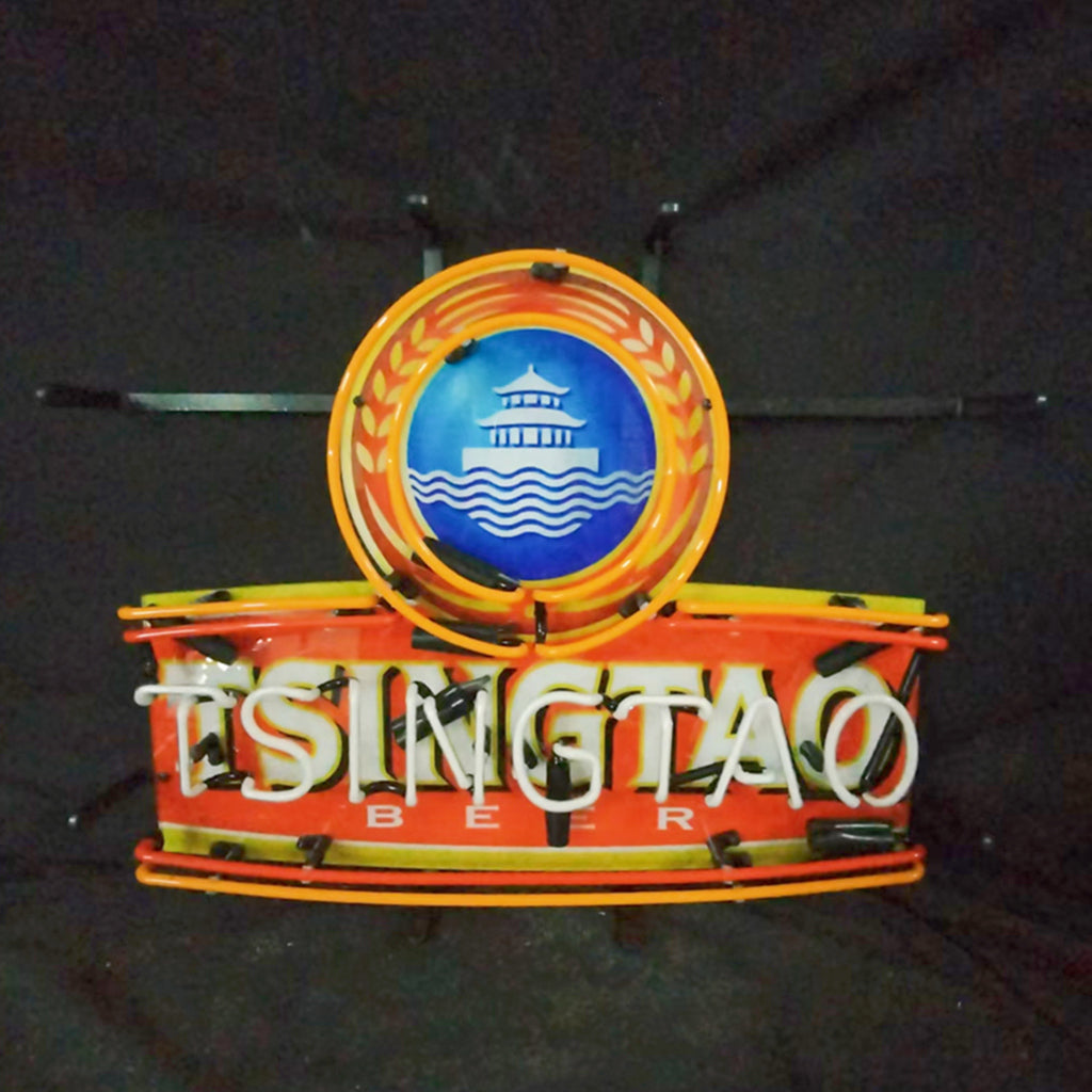 Neon sign featuring a blue circular emblem with a white pagoda and waves, surrounded by an orange wreath above the text 'TSINGTAO BEER' in white neon letters on a red background.