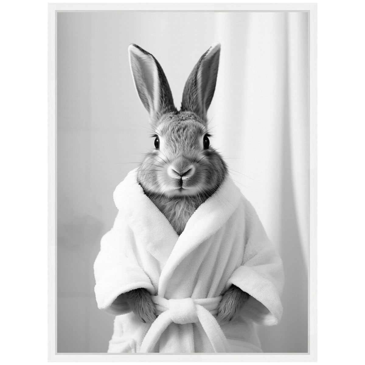 Black and white photo of a rabbit wearing a white bathrobe, standing upright against a simple backdrop with a soft curtain, showing its ears pointed up and hands tucked in the robe.