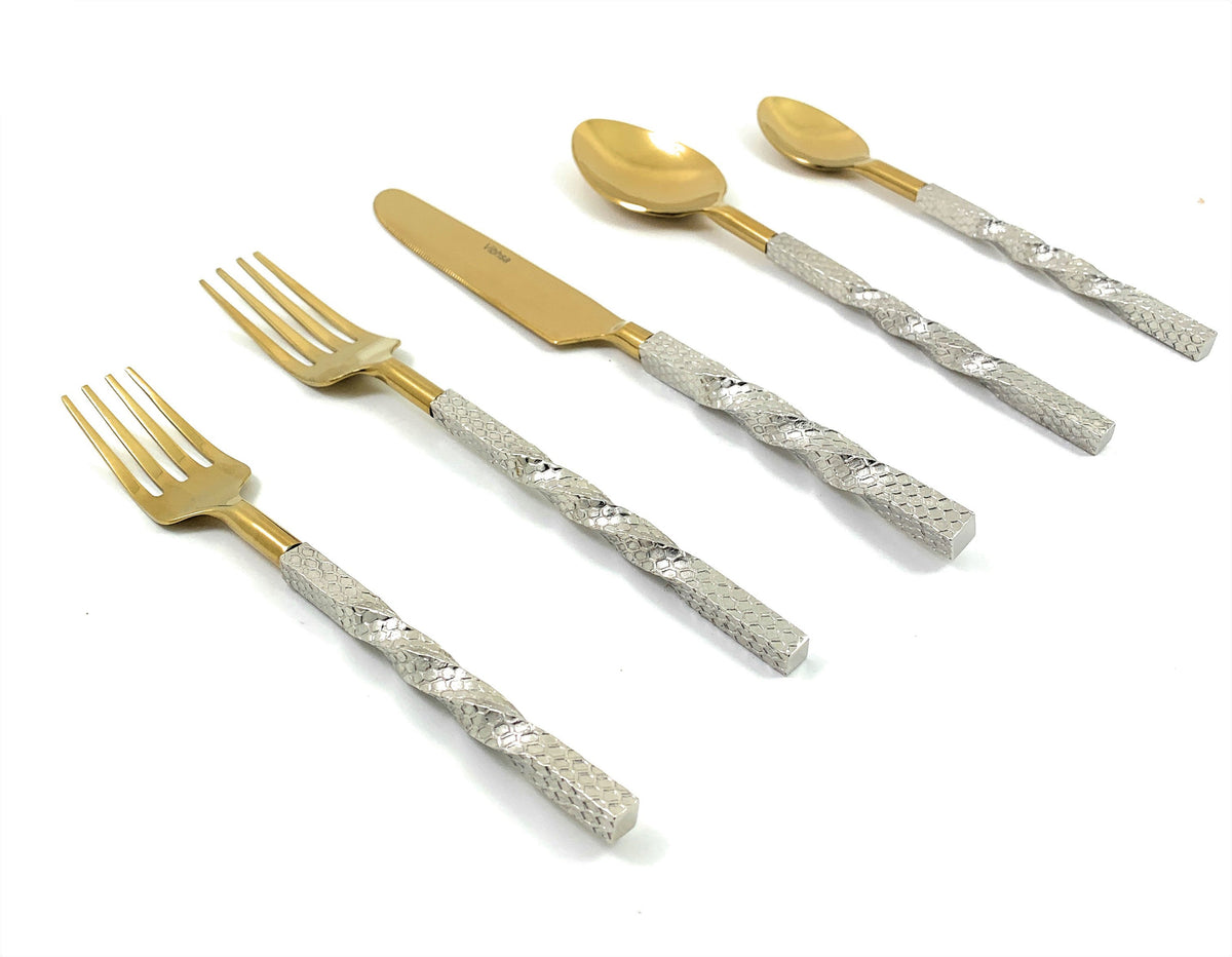 Golden stainless steel flatware set arranged on a dark wooden table