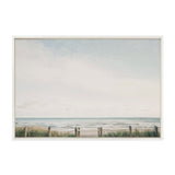 Framed canvas showing a calm ocean view with pale blue sky, gentle waves, sandy beach, and foreground dune grass behind a simple wooden fence.