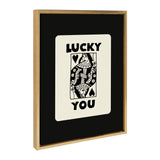Framed black and white canvas featuring a stylized 'Lucky You' playing card with floral details and bold lettering, set against a black background in a wood frame.