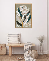 Framed abstract protea flower artwork with gray, beige, dark green, and white tones hanging above a wooden bench with striped cushion and draped textile in a minimalist room.