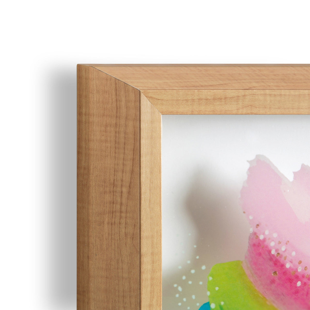 Close-up of light wood corner frame with simple mitered joint surrounding a watercolor print showing pink and green abstract shapes on white background