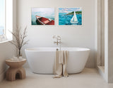 White freestanding bathtub with beige towel draped over the edge, placed below two framed paintings of a red canoe and a sailboat on water, in a minimalist bathroom.