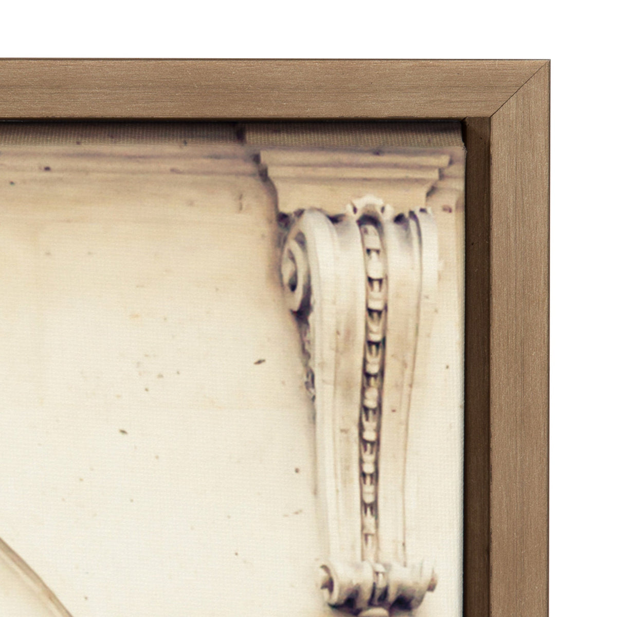 Close-up of a beige carved architectural detail with a scroll and bead pattern, bordered by a medium wood frame corner with mitered edges.