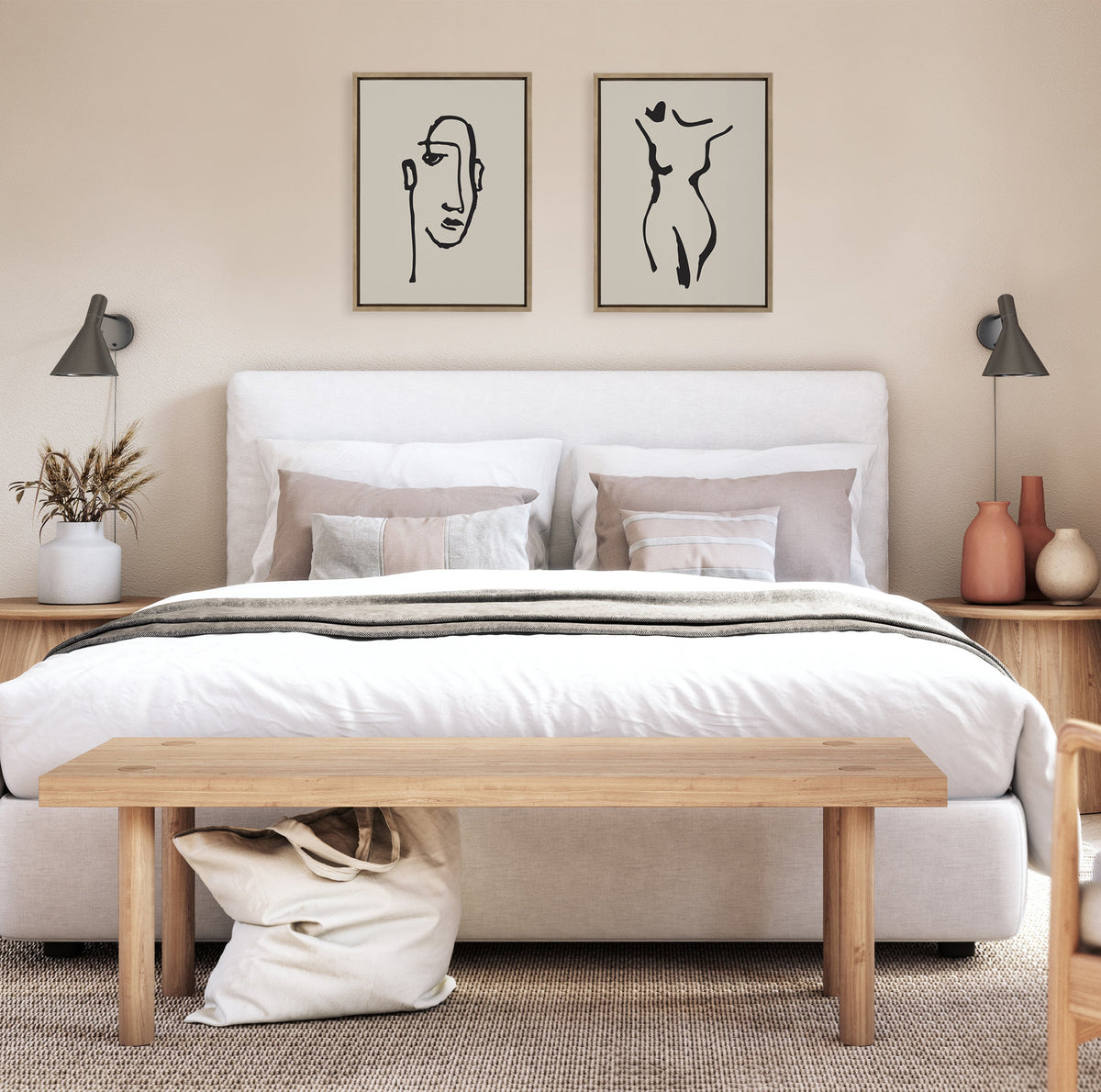 Neutral-toned bedroom with white upholstered bed, wooden bench at foot, two framed minimalist black line art prints of a face and a body above the headboard, and matching wooden nightstands with lamps.