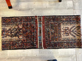 Vintage Kurdish Qochan runner rug with rich, dark red and brown tones, geometric patterns, and contrasting beige rectangular central motifs, laid on light wood floor.