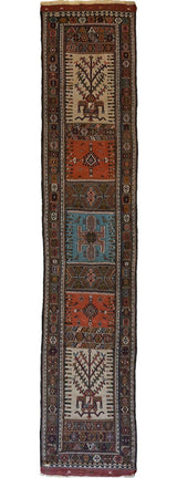 Long narrow Kurdish Qochan runner rug with repeating geometric medallions in rust, blue, cream, and dark brown, featuring symmetrical tribal motifs and detailed floral borders.