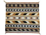 Rectangular vintage Navajo rug with horizontal geometric patterns in black, white, tan, and rust colors featuring chevrons and zigzags, with knotted tassels at corners.