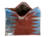 Top-down view of a folded vintage Baluch salt bag rug with red and blue triangular patterns and woven textured fibers.